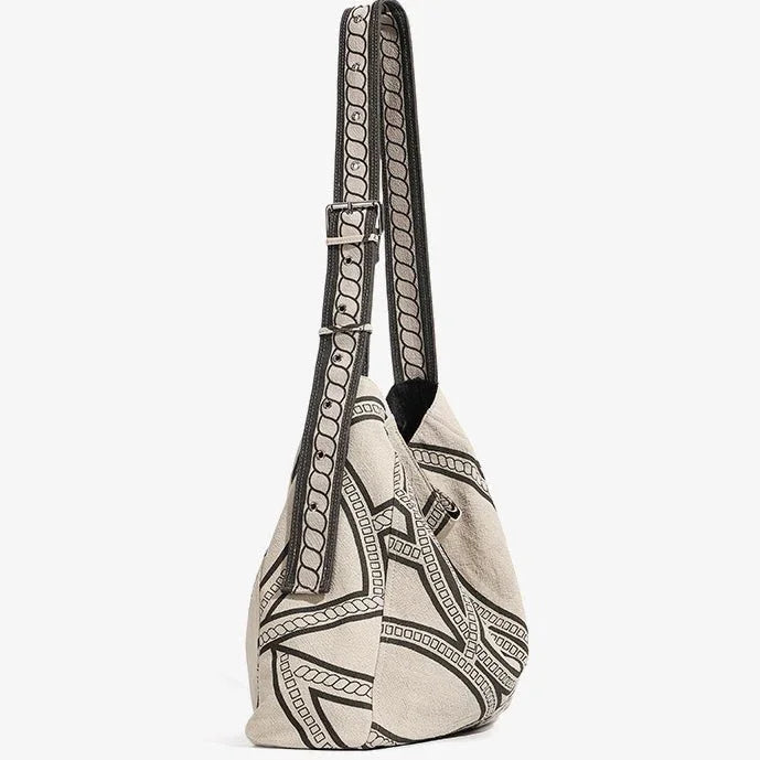 Beige canvas shoulder bag with black geometric pattern and adjustable strap