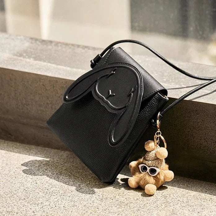 Black leather crossbody bag with bunny design and plush teddy bear keychain