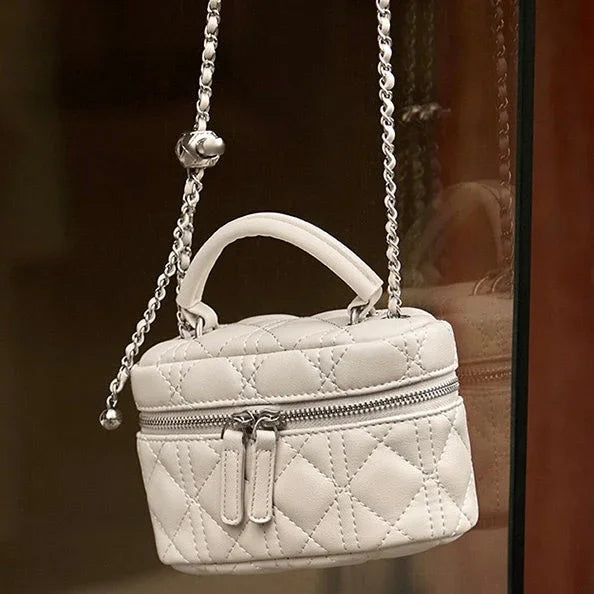 Quilted white leather mini handbag with top handle and chain strap, zip closure
