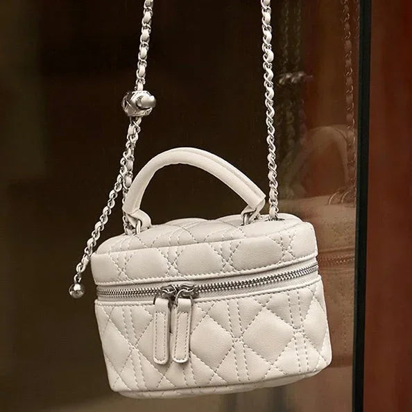 Quilted white leather mini handbag with top handle and chain strap, zip closure