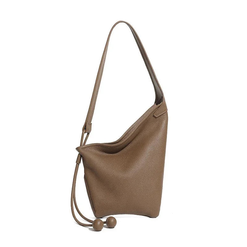 Taupe leather shoulder bag with drawstring accents and modern minimalist design on white background