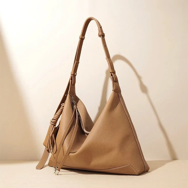 Beige leather hobo handbag with adjustable strap on neutral background