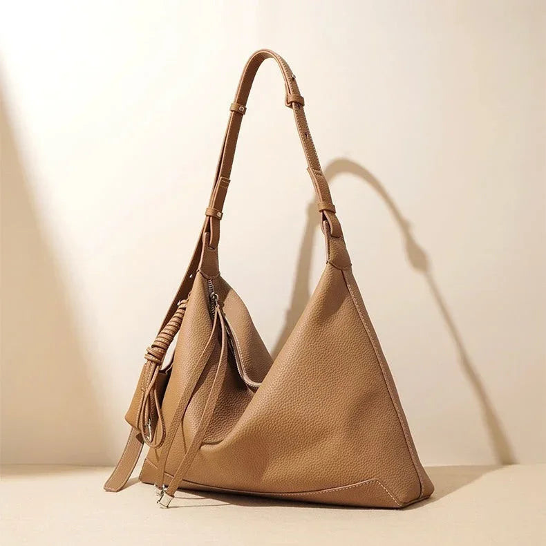 Beige leather hobo handbag with adjustable strap on neutral background