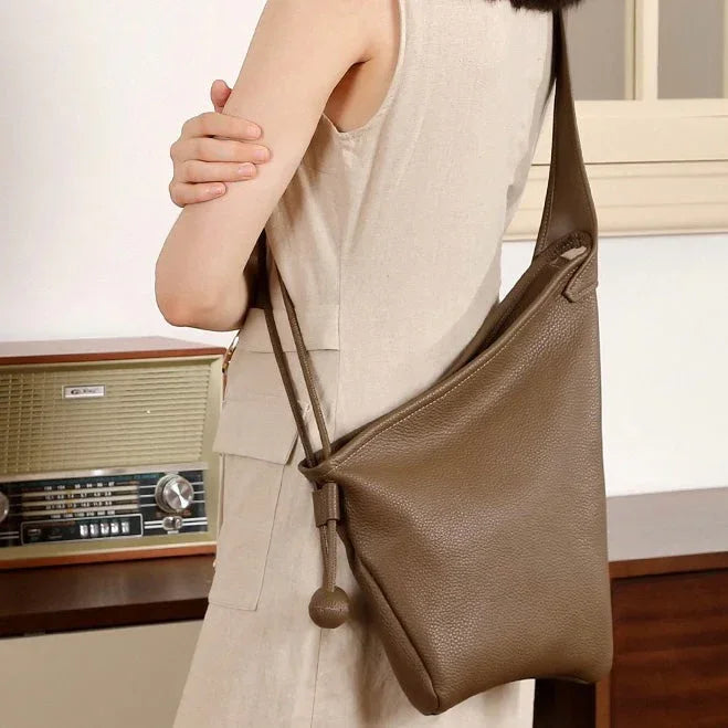 Woman in beige dress wearing brown leather shoulder bag, vintage radio in background