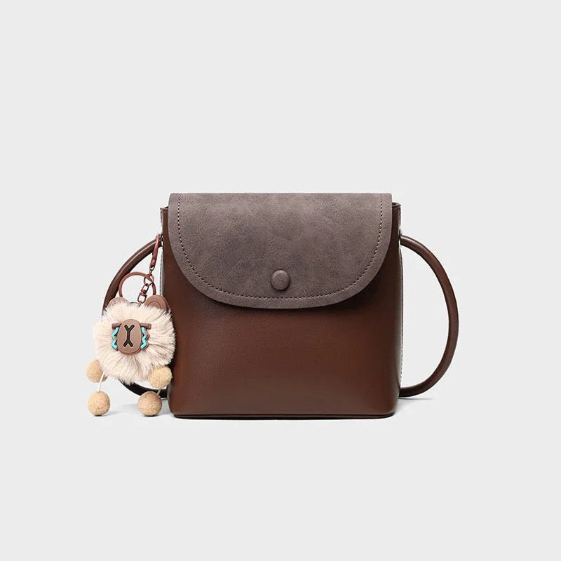 Brown crossbody purse with gray flap and plush bear keychain accessory