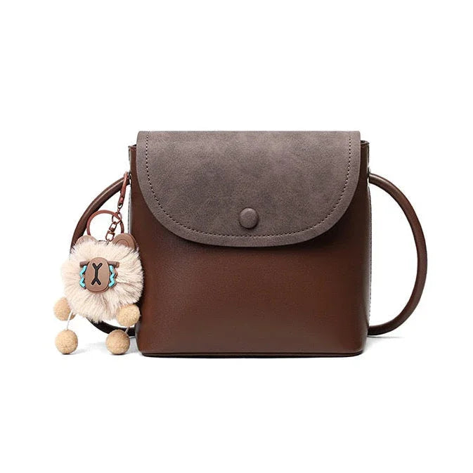 Brown crossbody purse with gray flap and plush bear keychain accessory
