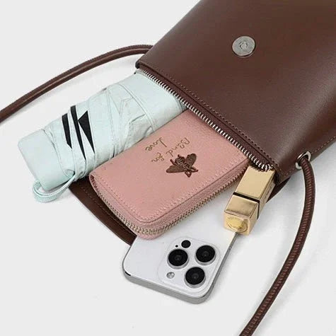 Brown crossbody purse with a folded umbrella, pink wallet, gold lipstick, and smartphone