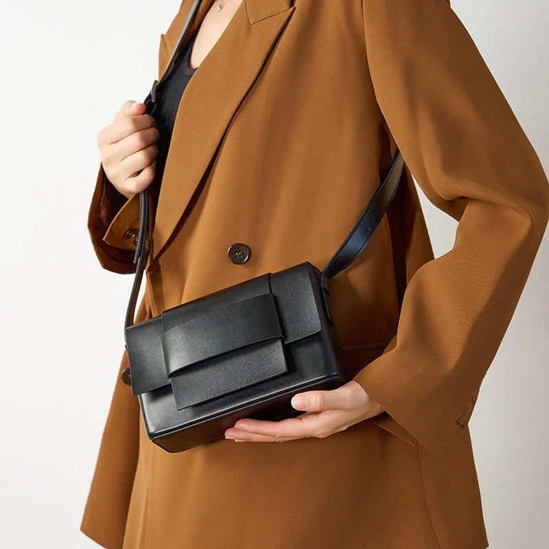 Woman in brown blazer holding stylish black leather crossbody bag