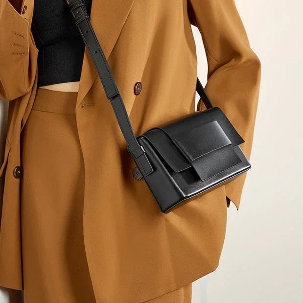 Woman in camel suit with black crop top and black leather crossbody bag