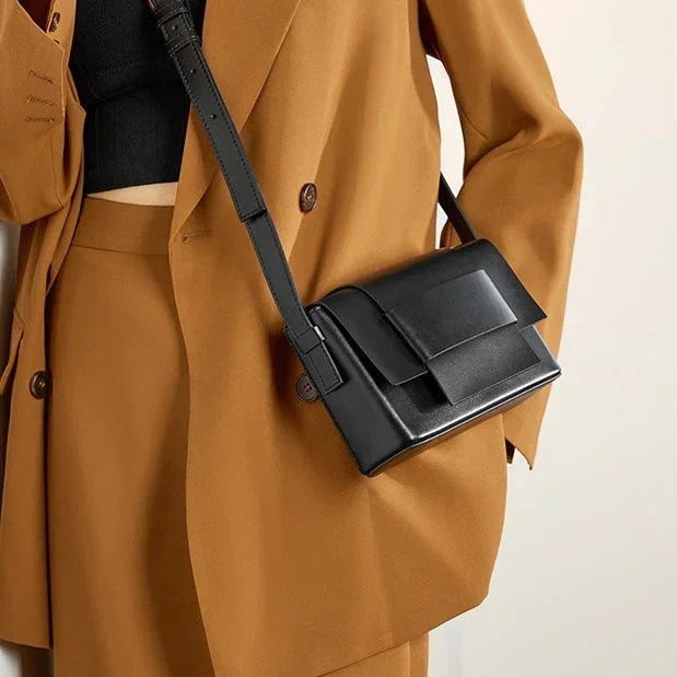 Woman in camel suit with black crop top and black leather crossbody bag