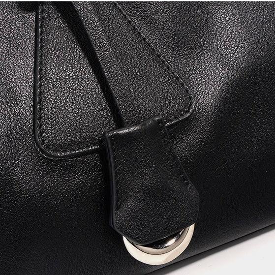 Close-up of black leather handbag with silver buckle detail