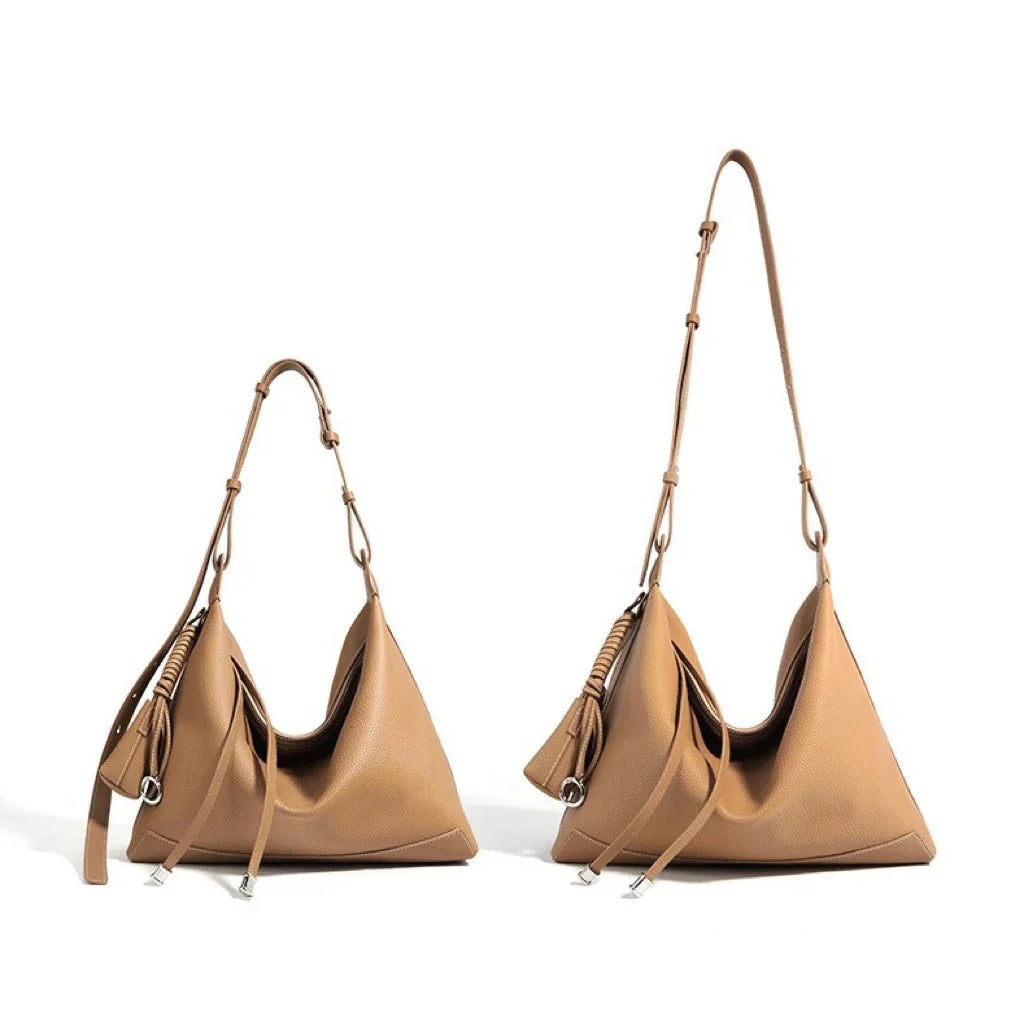 Two tan leather hobo bags with adjustable straps and silver hardware on white background