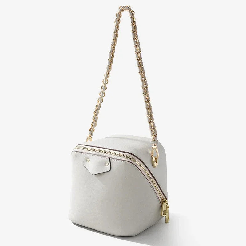 White leather box bag with gold chain strap and zipper, minimalist purse on white background