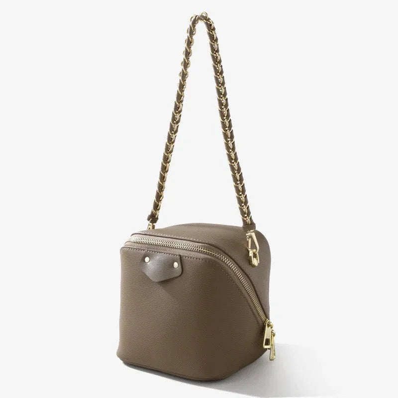 Taupe leather box bag with gold chain strap and zipper, stylish cube purse on white background