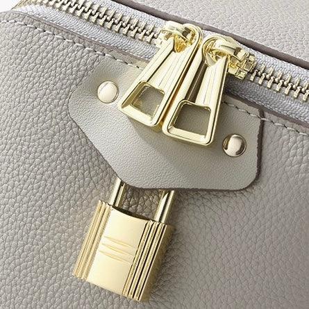 Close-up of a grey leather bag with gold zippers and a gold padlock detail