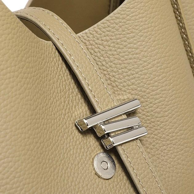 Closeup of beige pebbled leather handbag with silver hardware and magnetic clasp