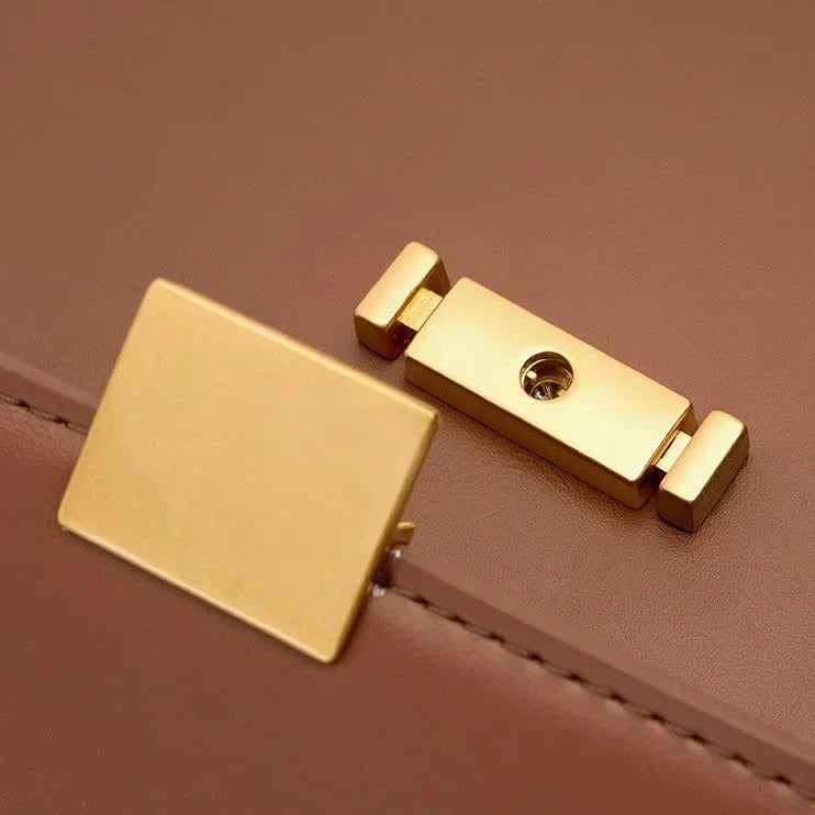 Close-up of gold rectangular clasp on brown leather handbag