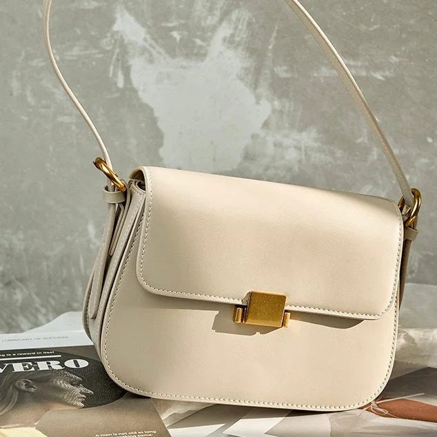 Beige leather shoulder bag with gold clasp on magazine, minimal fashion accessory