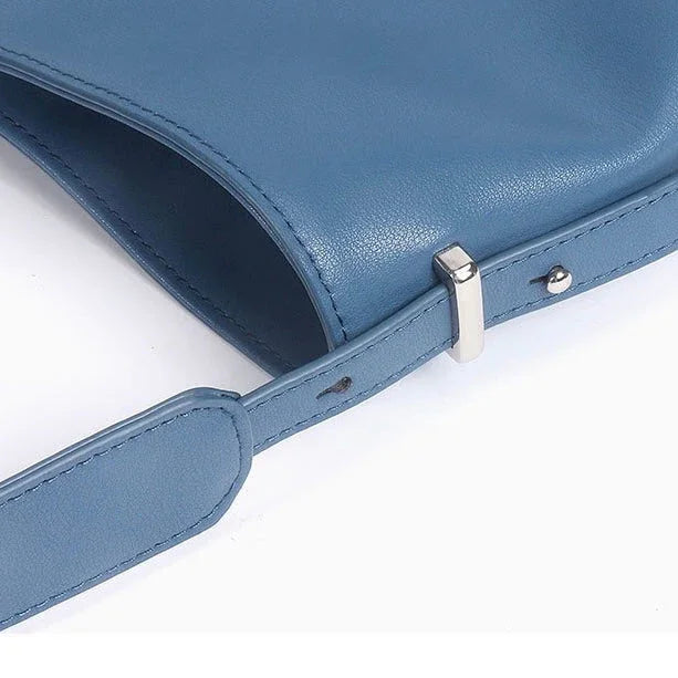 Blue leather shoulder bag with adjustable strap and silver buckle on white background