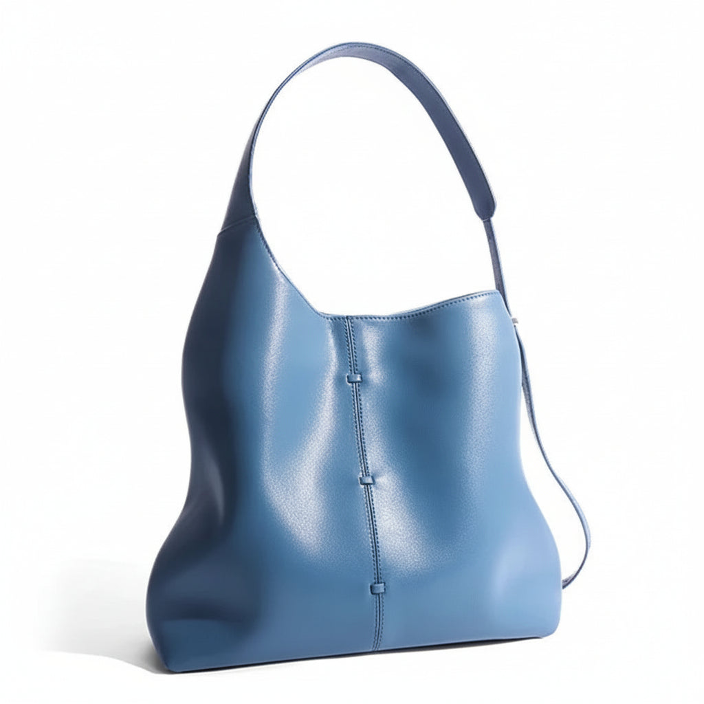 Minimalist blue leather shoulder bag with a wide strap on a white background