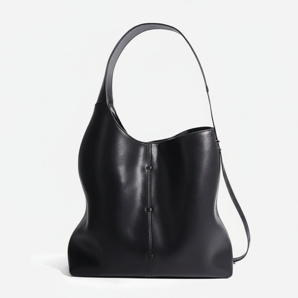 Black leather hobo bag with wide shoulder strap and minimalist seam detail, studio background