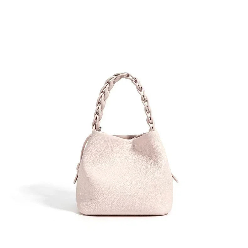 Beige leather handbag with braided handle on white background