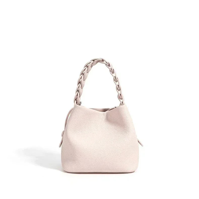 Beige leather handbag with braided handle on white background