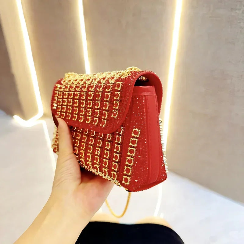 Hand holding red designer handbag with gold square stud accents under modern lighting