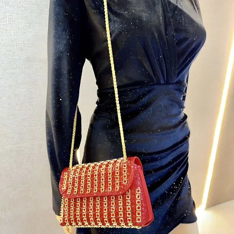 Red chain-embellished purse with gold strap on mannequin in a fitted black dress