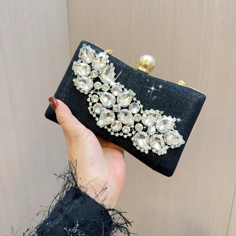Hand holding black clutch purse with large crystal rhinestones and pearl clasp