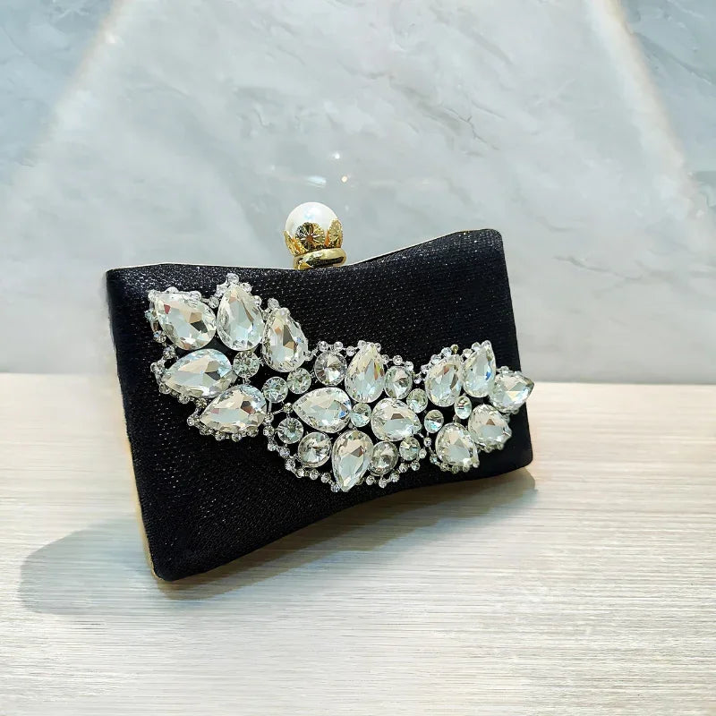 Black evening clutch with crystal rhinestone embellishments and pearl clasp on table