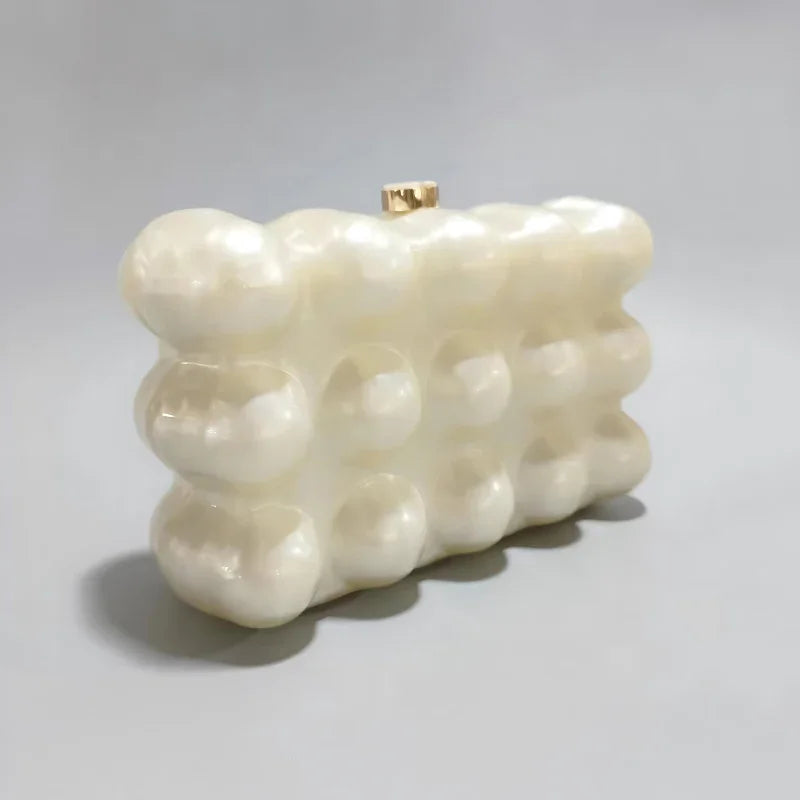 White pearl acrylic bubble clutch purse with gold clasp on a light gray background