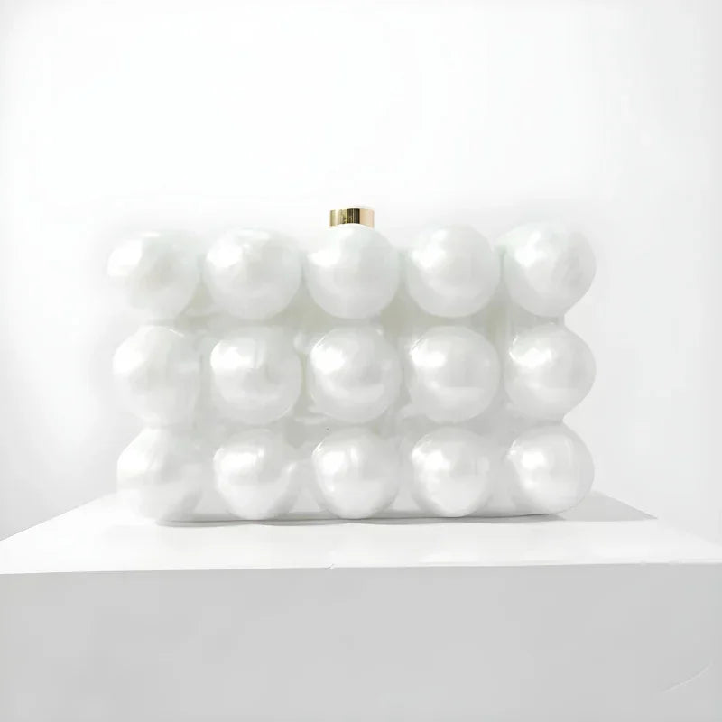 White pearl bubble clutch purse with gold clasp on white display pedestal