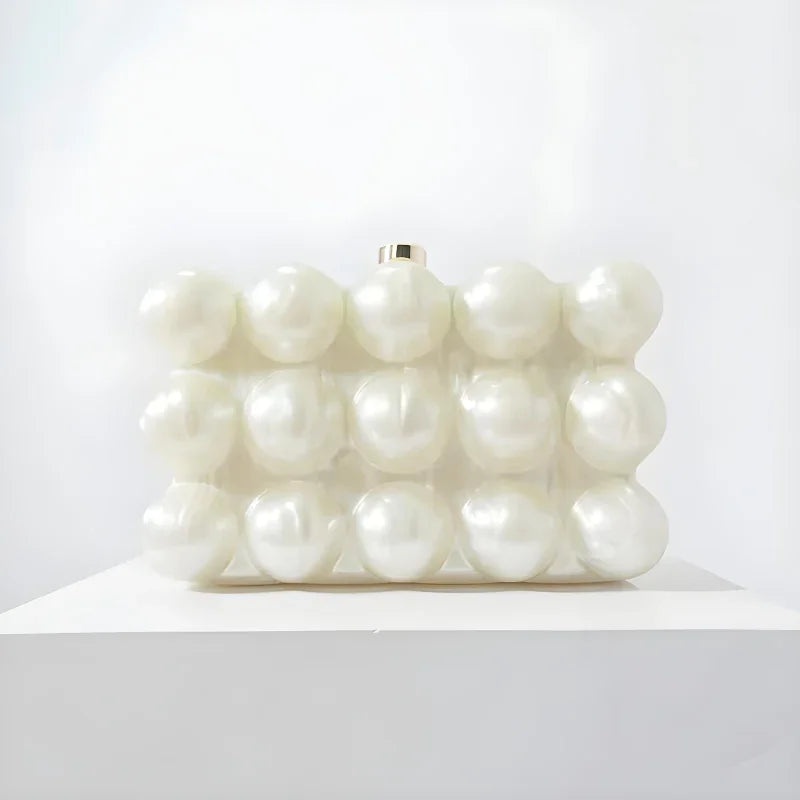 White clutch bag with raised pearl-like bubbles on display against a plain white background