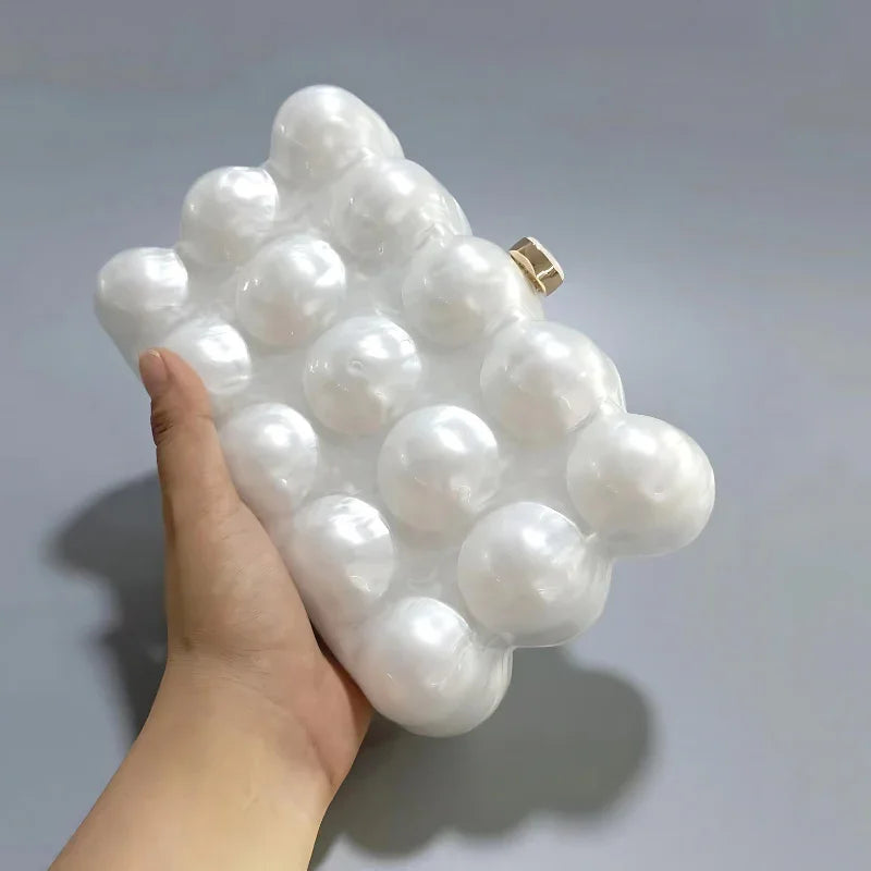 Hand holding a pearl bubble clutch bag with a glossy, modern geometric design