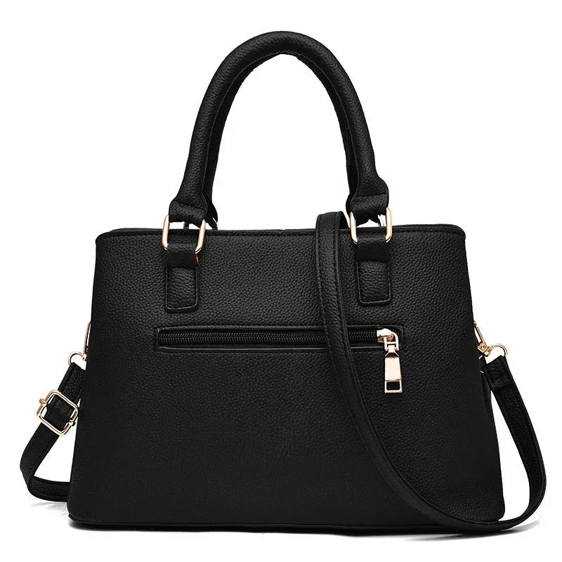 Black leather handbag with gold hardware, top handles, and detachable shoulder strap