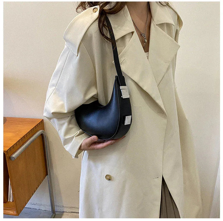 Woman in beige trench coat with black crescent shoulder bag