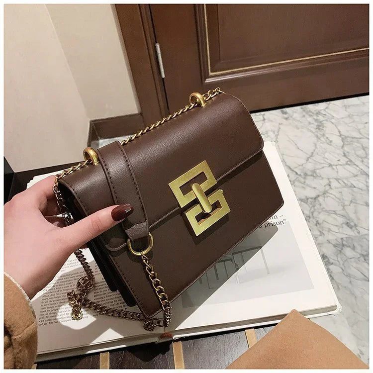 Brown leather shoulder bag with gold chain strap and geometric metal clasp on magazine