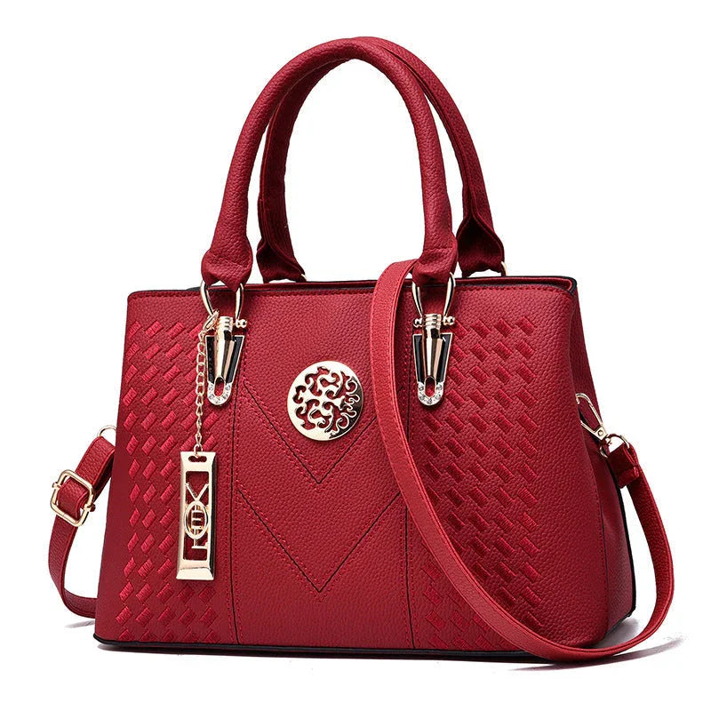 Elegant red leather handbag with gold hardware and decorative textured pattern