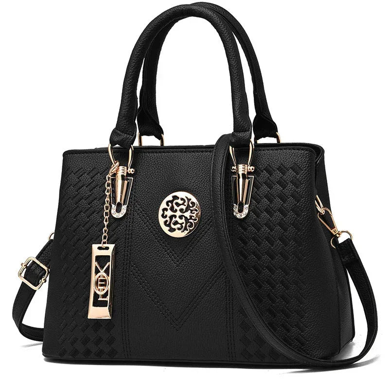 Black leather handbag with gold hardware, textured pattern, and decorative emblem