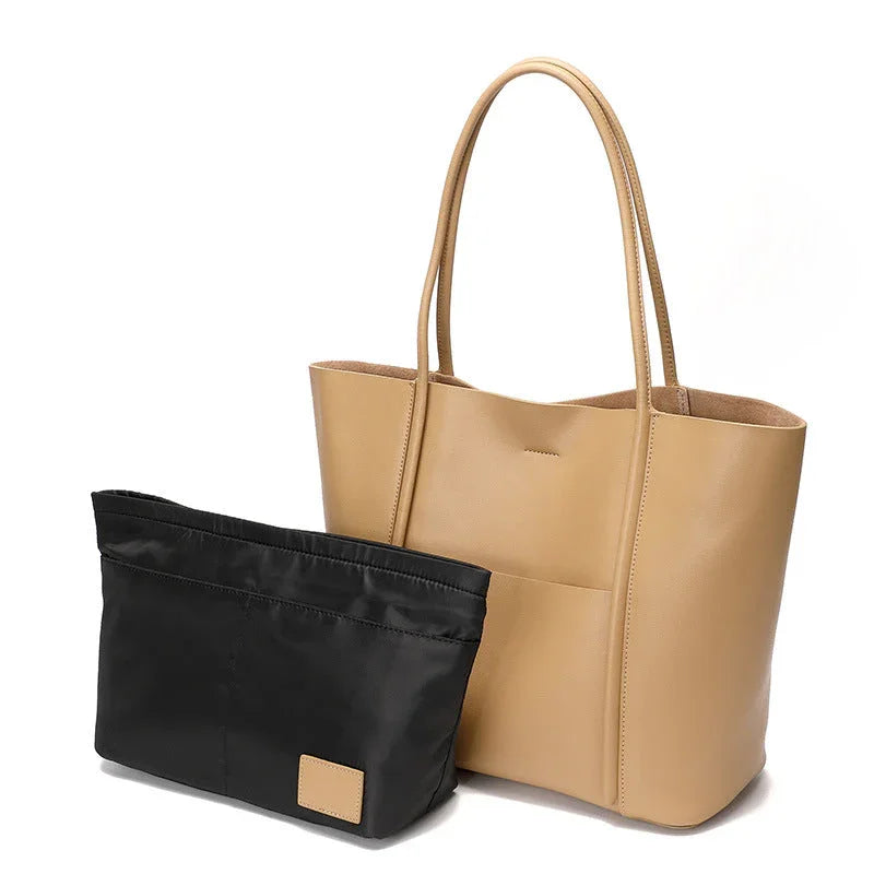 Beige leather tote bag with black removable organizer insert on white background