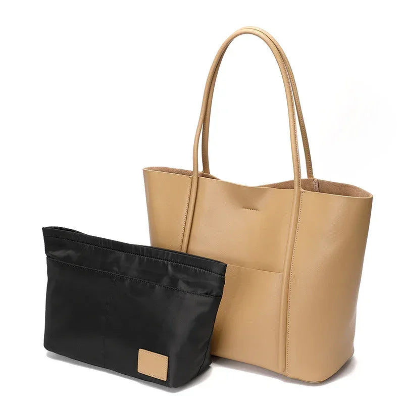 Beige leather tote bag with black removable organizer insert on white background