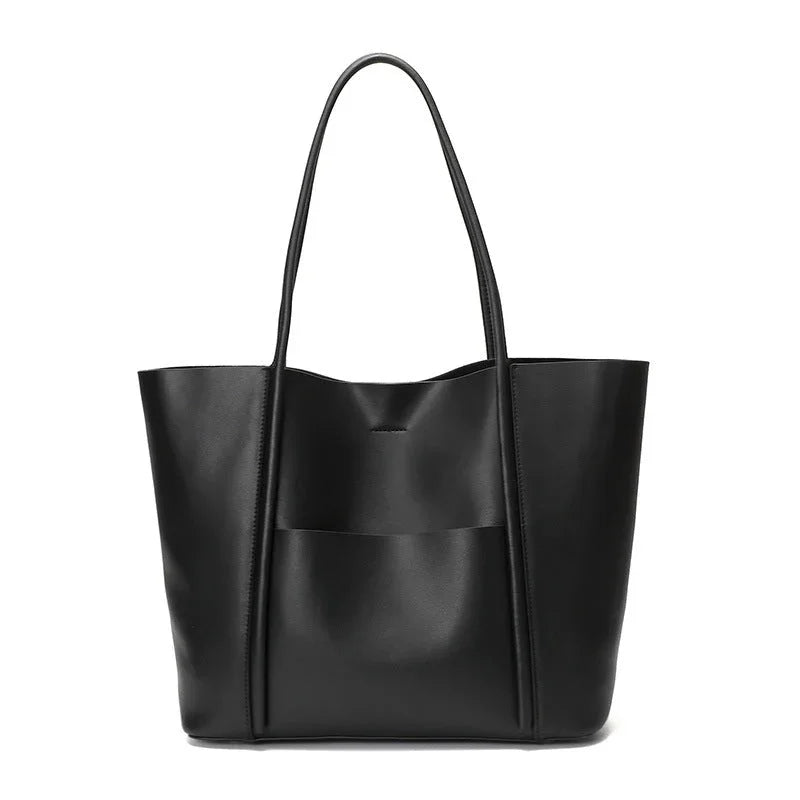 Black leather tote bag with long handles and front pocket on white background