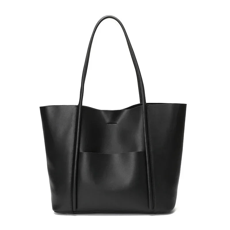 Black leather tote bag with long handles and front pocket on white background