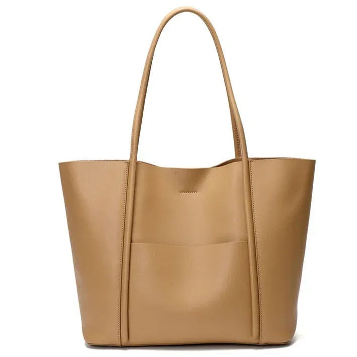 Tan leather tote bag with exterior pocket and double handles on white background