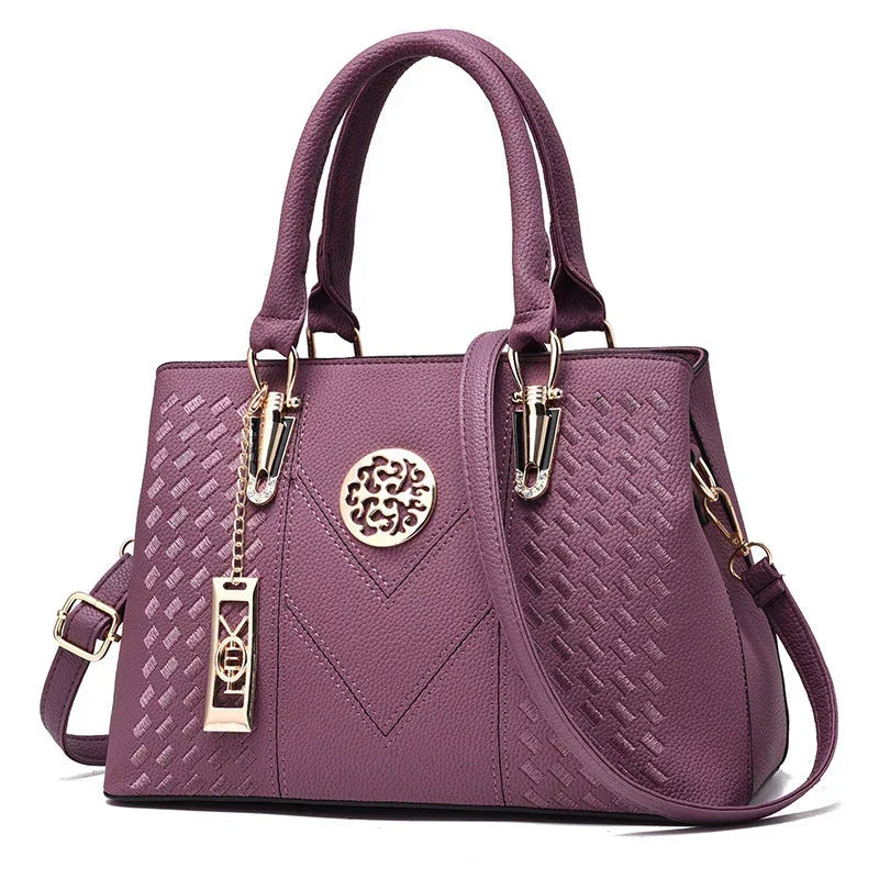 Purple leather handbag with gold hardware, double handles, and embossed geometric patterns