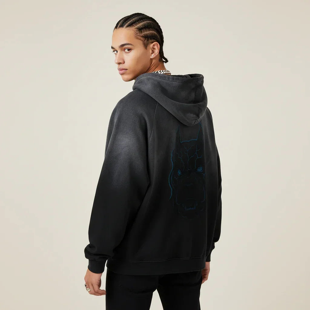 Person wearing a black hoodie with a Pitbull dog graphic on the back against a beige background | Rebooters