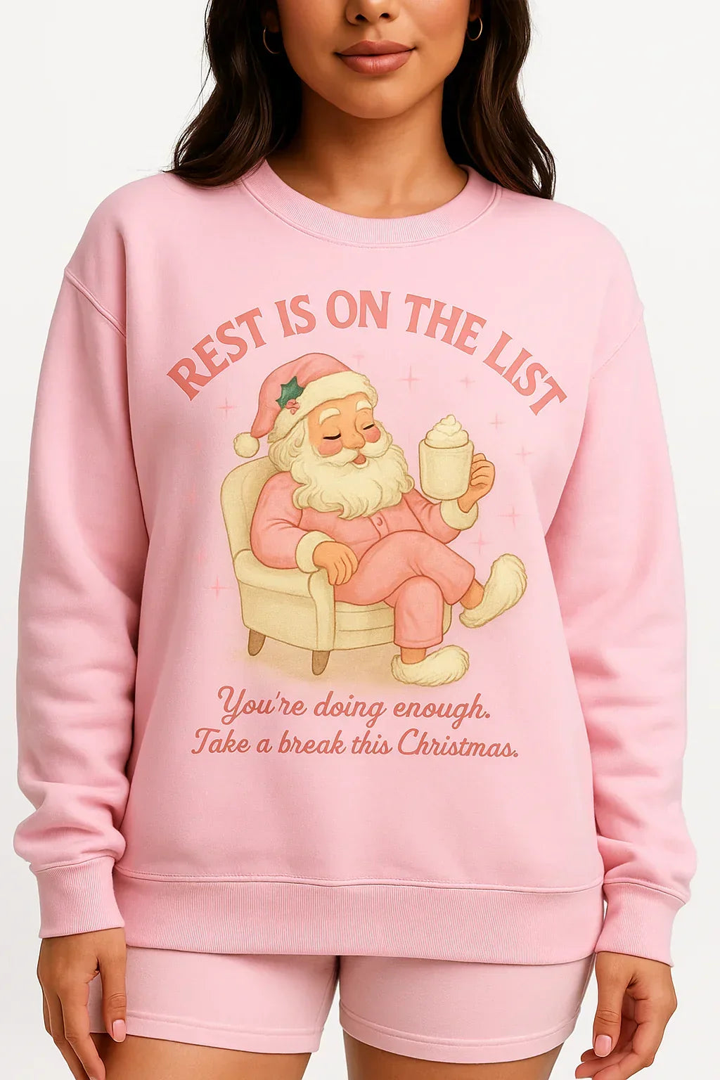 Pink sweatshirt with Santa Claus graphic and text on a white background