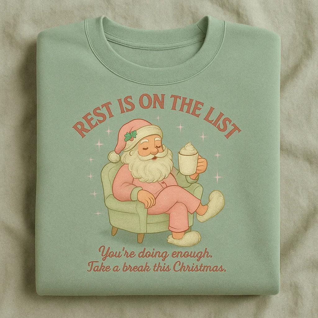 Folded mint green t-shirt with Santa Claus graphic and text on a beige background