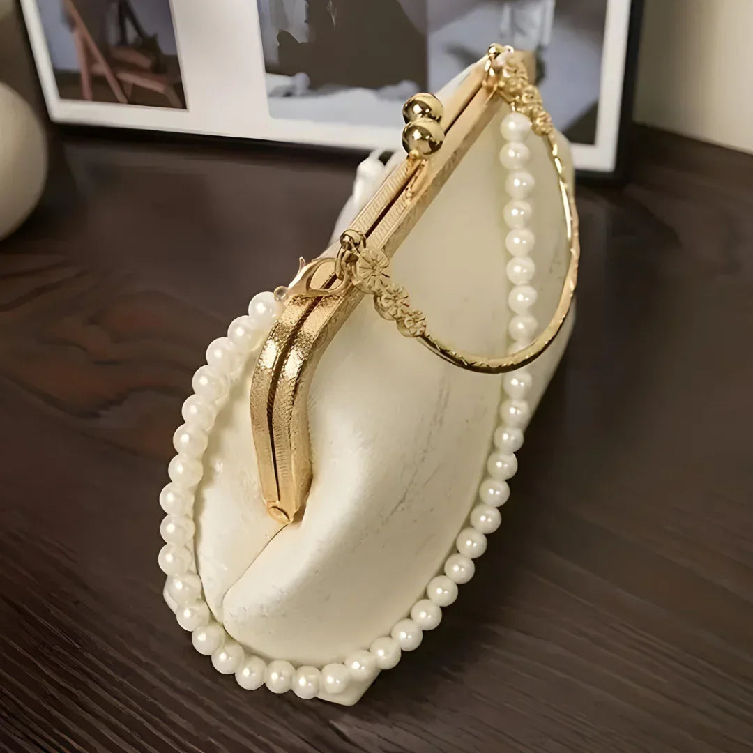 Elegant white pearl beaded handbag with gold clasp on dark wood table